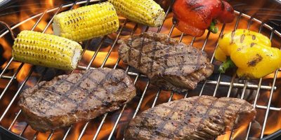 A Pan Filled With Meat And Vegetables Cooking On A Grill